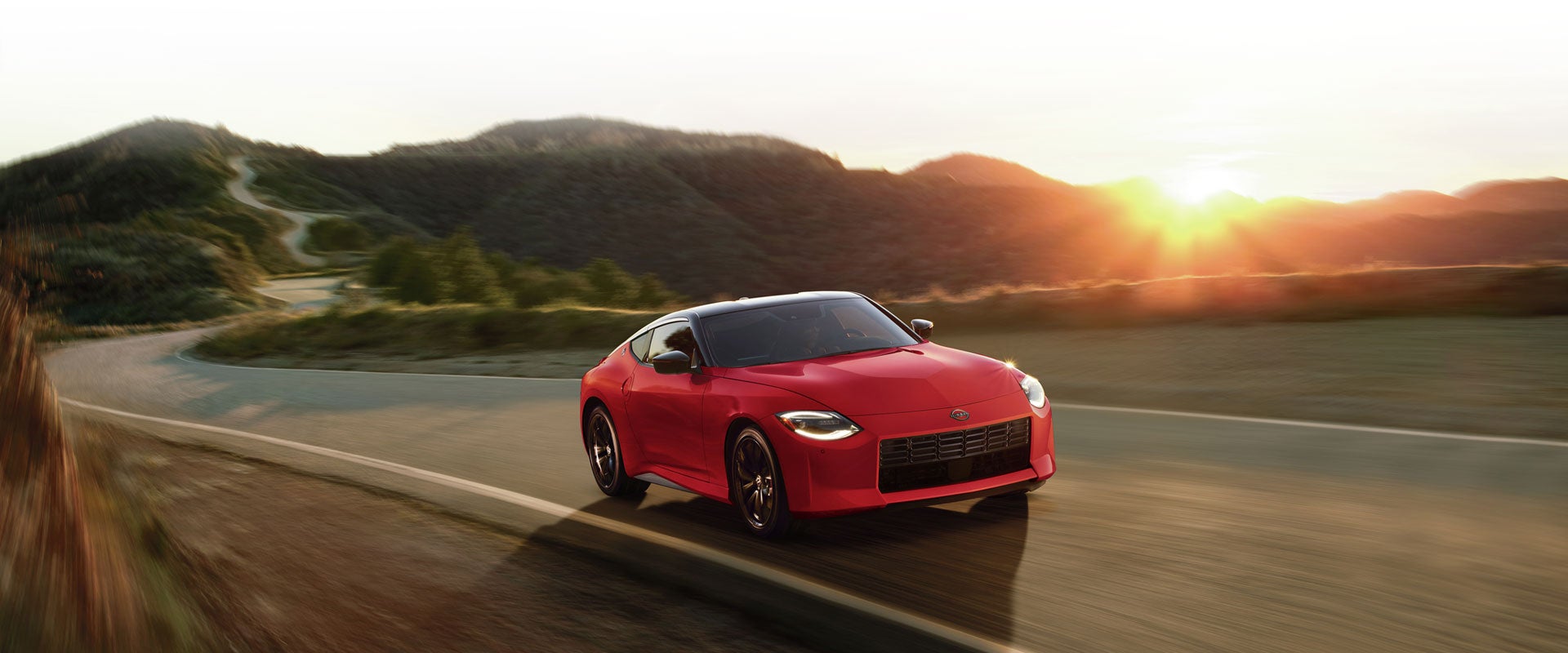 2025 Nissan Z in red driving on a rural road at speed